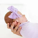 Newborn swaddled in lavender wearing the Lou Lou & Company Lace Bow Headband in Lavender