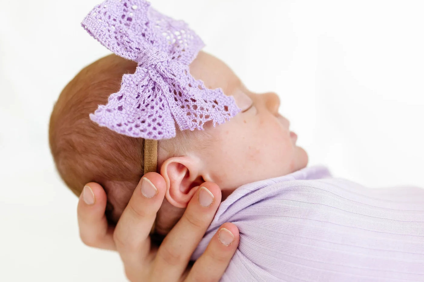 Newborn swaddled in lavender wearing the Lou Lou & Company Lace Bow Headband in Lavender