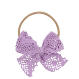 Lou Lou & Company Lace Bow Headband in Lavender, a purple crochet lace bow on a soft nylon band