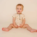 Smiling baby sitting in the Lou Lou & Company Romper in Austin checkered print