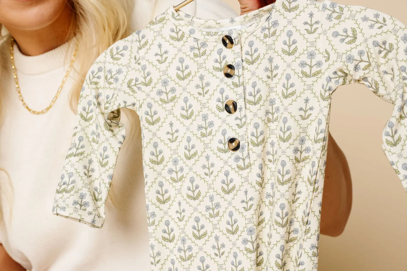 Woman holding up the Lou Lou & Company Romper in Etta on a hanger
