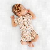Newborn with a bow lying on a blanket in the Lou Lou & Company Romper in Rachel floral