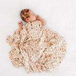 Newborn in the Lou Lou & Company Romper in Rachel lying on a matching floral swaddle