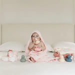Baby in a pink hooded towel sitting on a bed with the Lou Lou & Company Rubber Duckies Set