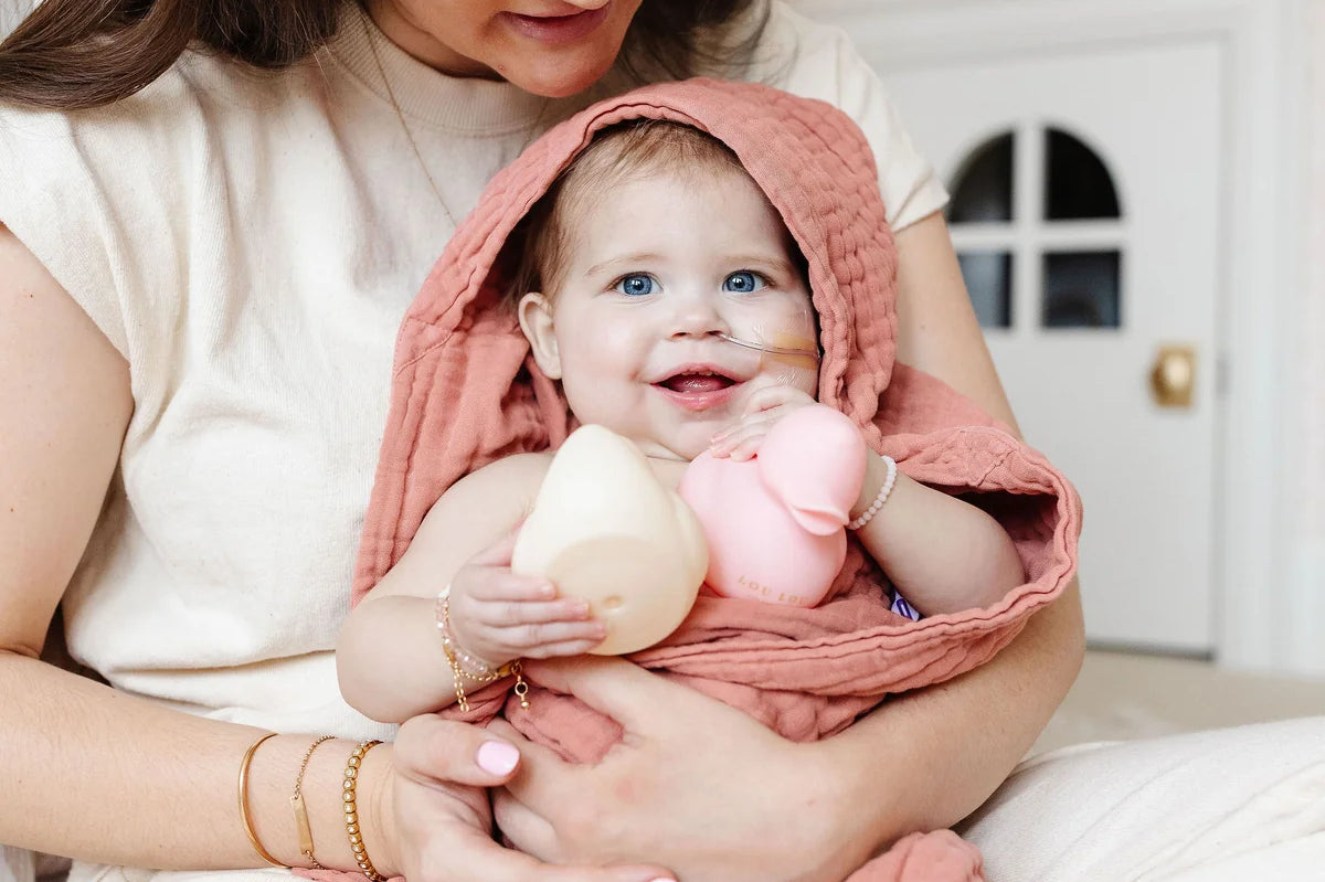 Mother holding a baby in a pink towel with Lou Lou & Company Rubber Duckies in cream and pink