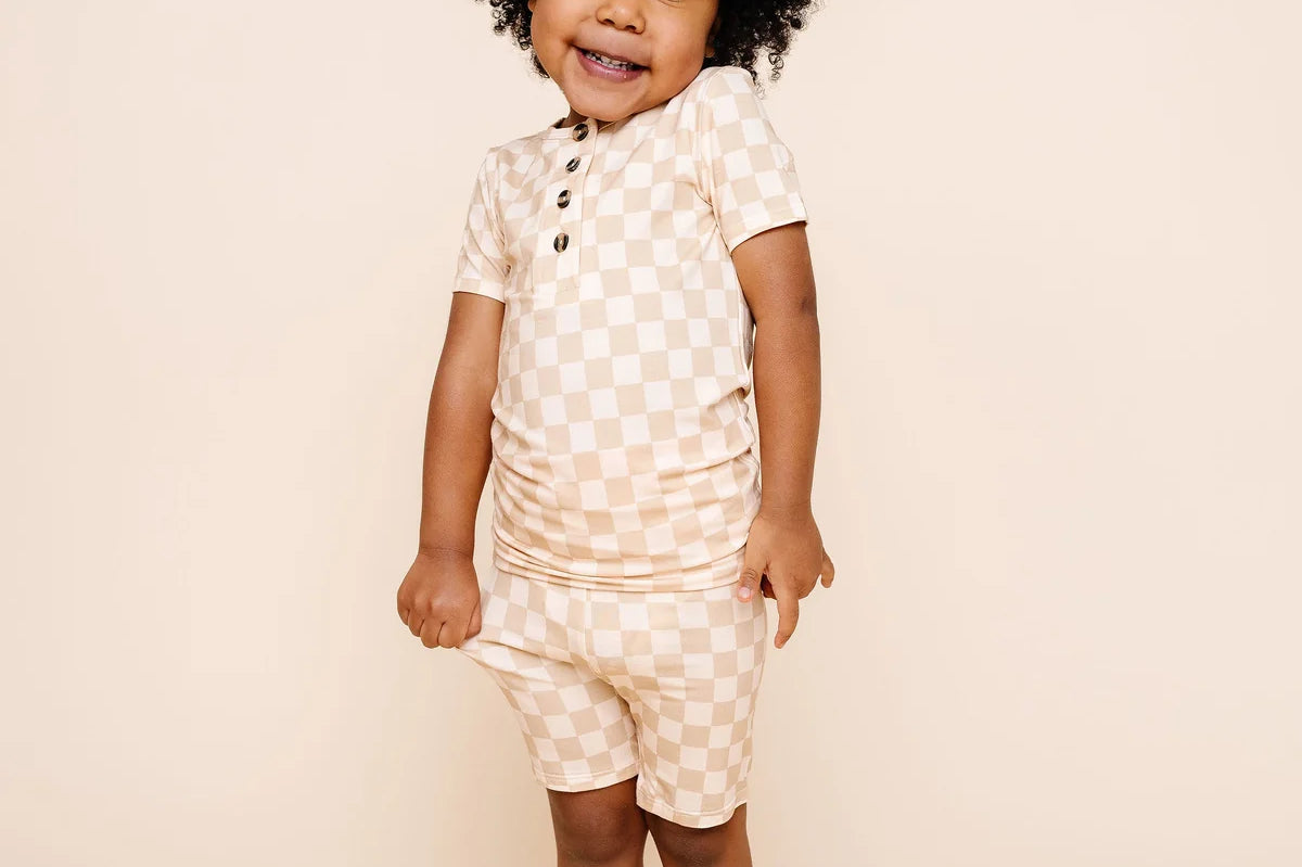 Smiling toddler with curly hair wearing the Lou Lou & Company Shortie Set in Austin checkered print