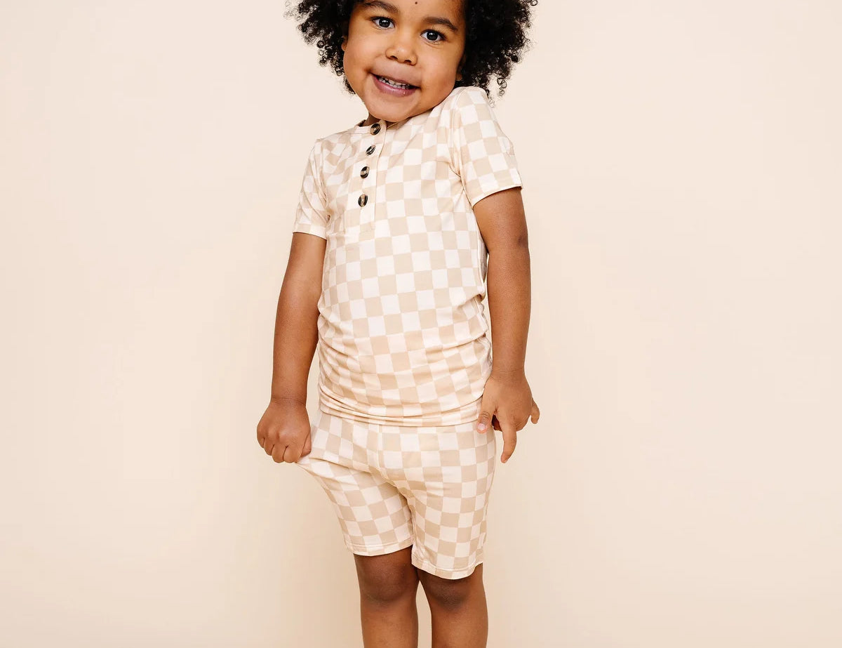 Smiling toddler with curly hair wearing the Lou Lou & Company Shortie Set in Austin checkered print