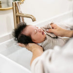 Newborn being bathed in a sink with a Lou Lou & Company Washcloth in Grey