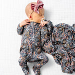Baby lying on a blanket wearing the Lou Lou & Company Zipper Footies in Bae with a matching floral swaddle