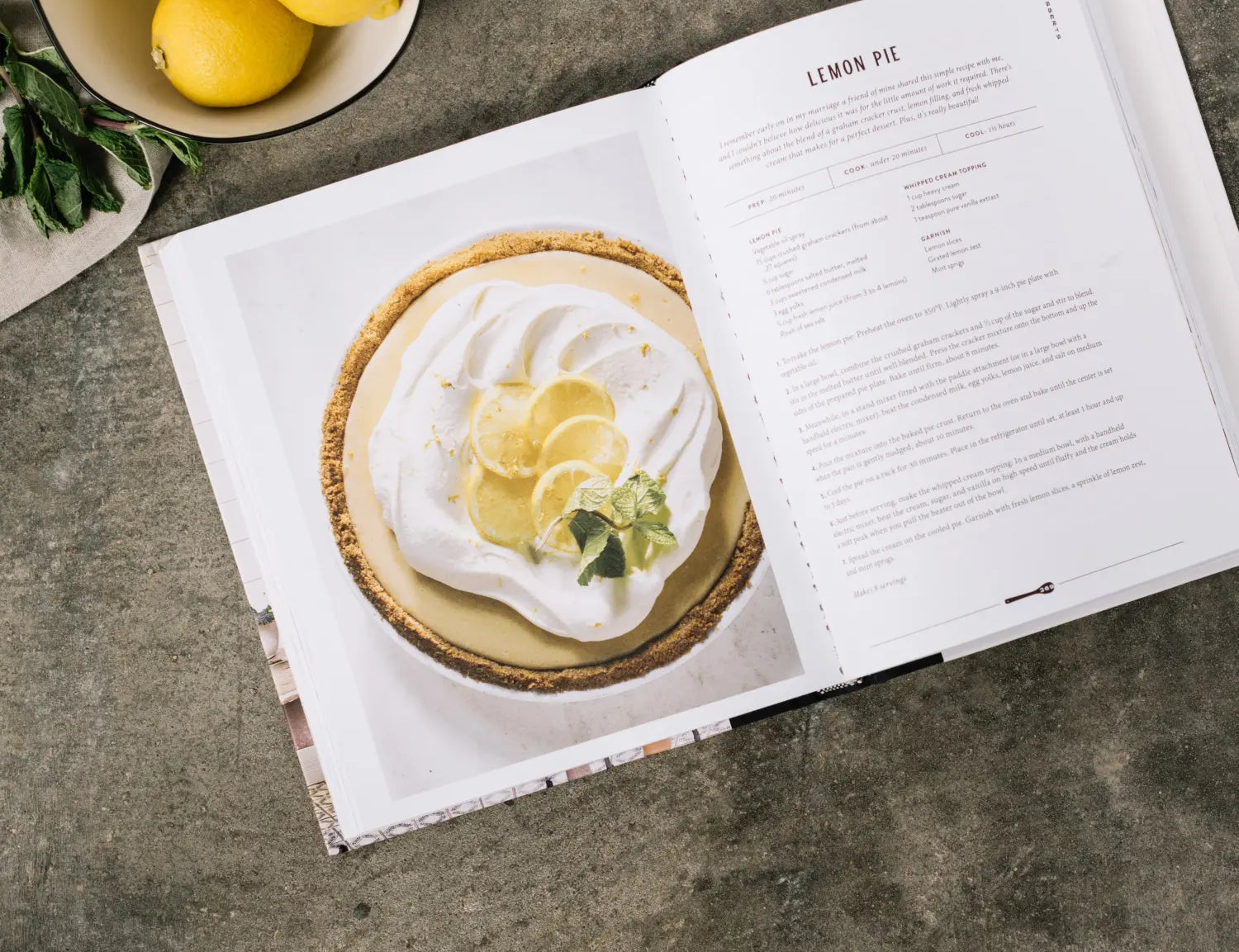Magnolia Table Cookbook Volume 1 open to the lemon pie recipe with a bowl of lemons