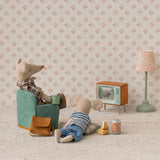 Maileg mouse in a chair watching the miniature Television with a lamp and floral wallpaper
