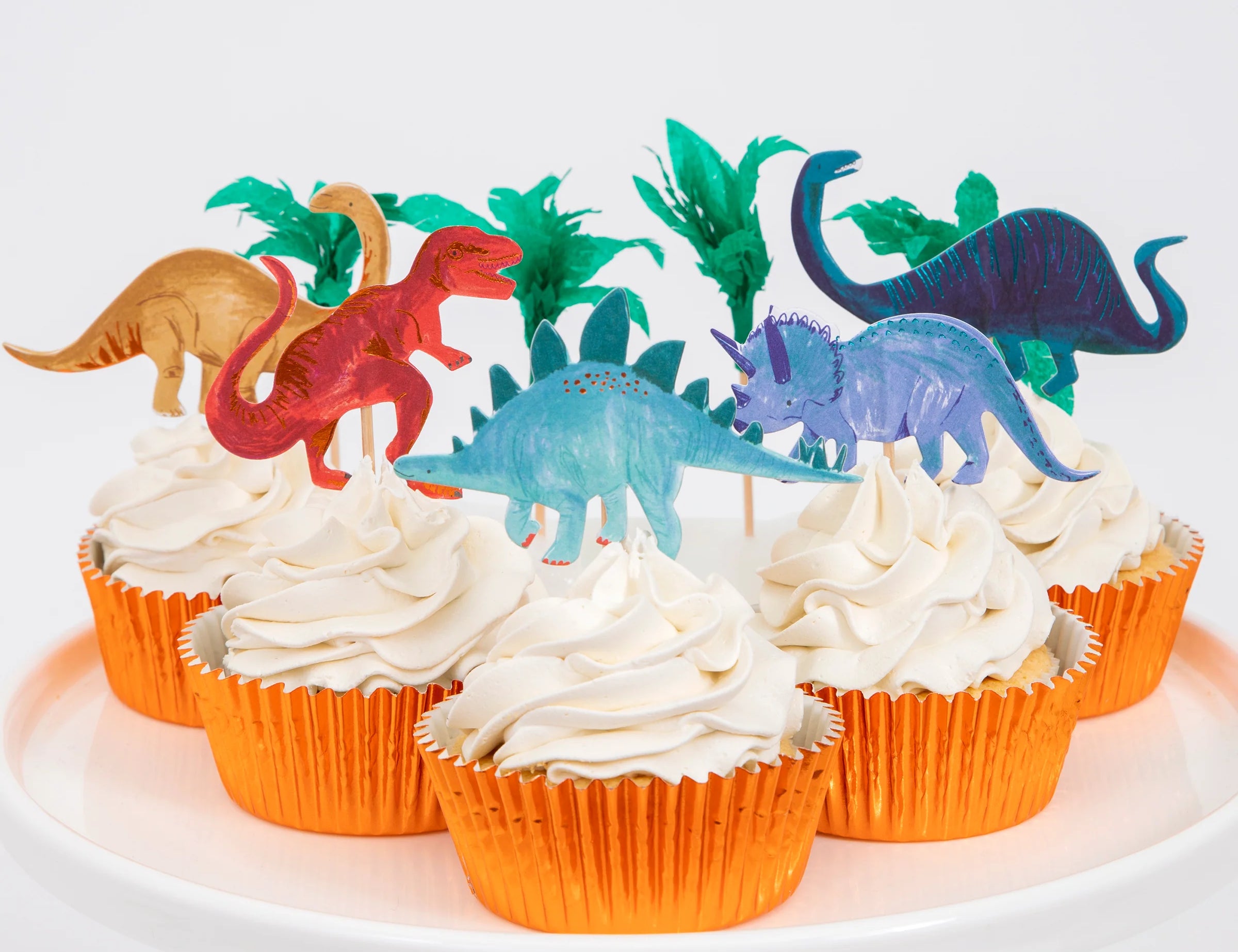 Meri Meri Dinosaur Kingdom Cupcake Kit, cupcakes in orange foil wrappers topped with dinosaur and palm toppers