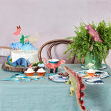 Dinosaur-themed party table with a cake, Meri Meri Dinosaur Kingdom cupcakes and plates