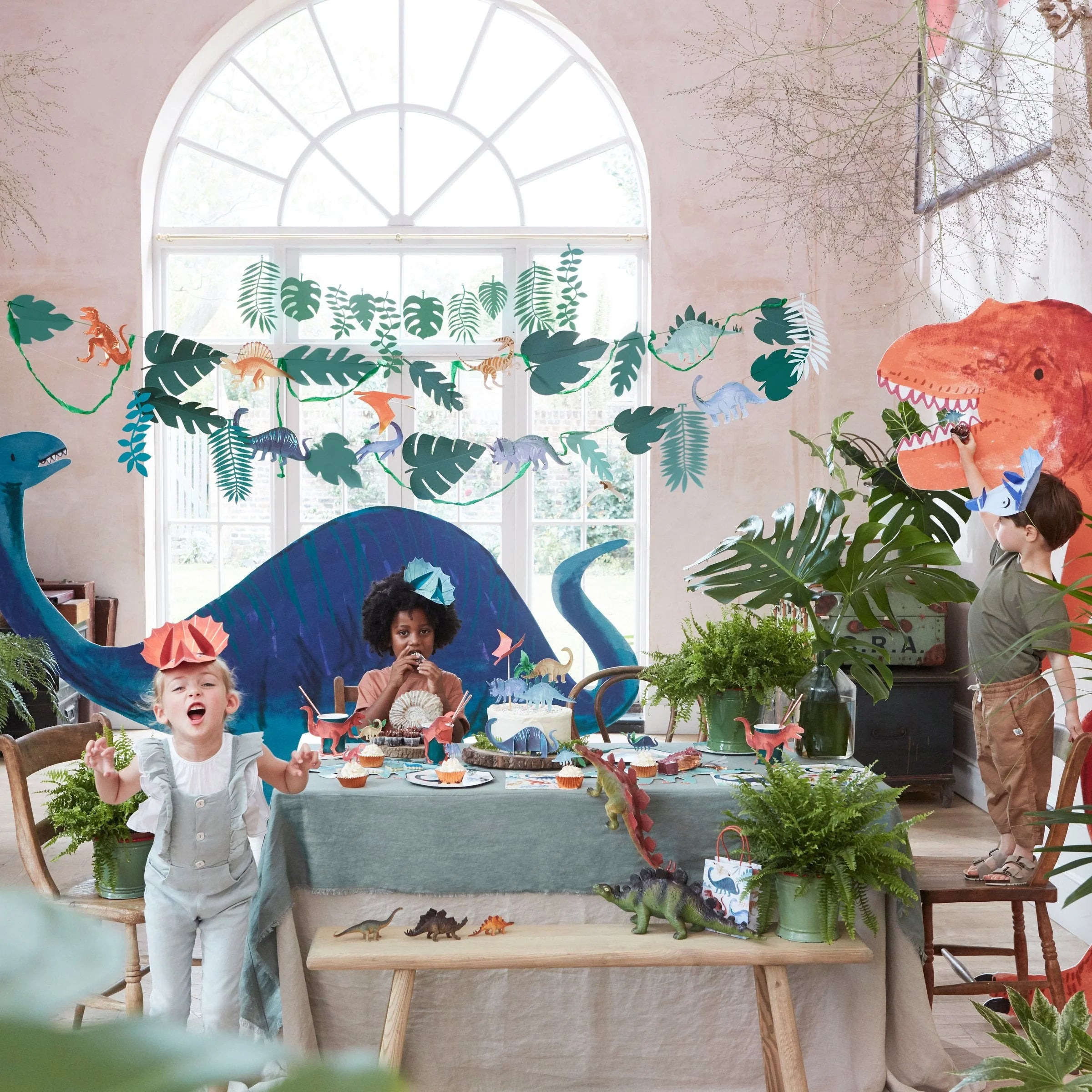 Meri Meri Dinosaur Kingdom Large Garland hung across a window at a children's dinosaur party
