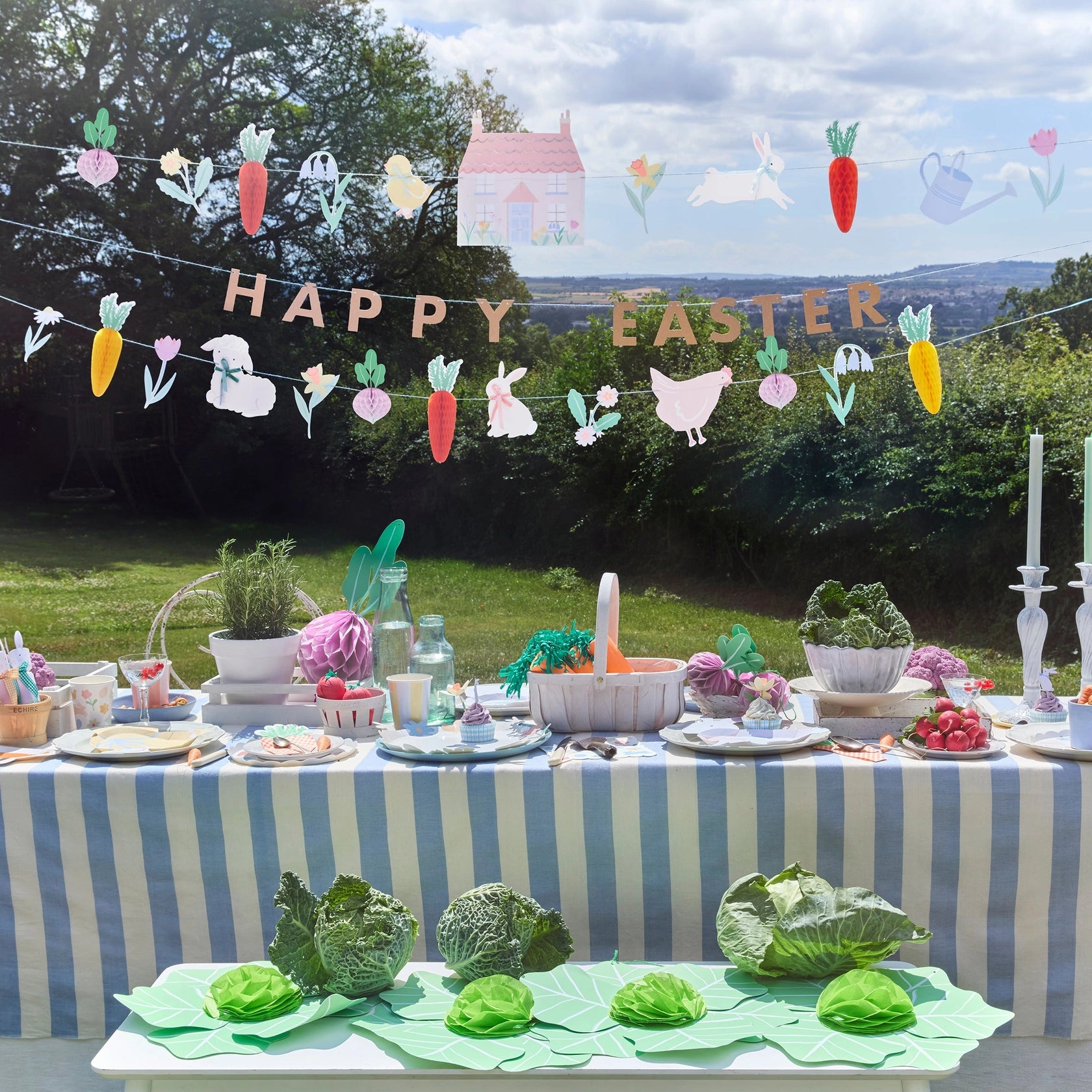 Meri Meri Easter Vegetable Garden Garland Set hung over an outdoor Easter table with cabbages and flowers