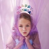 Girl under a purple tulle canopy wearing the Meri Meri Happy Birthday Glitter Headband