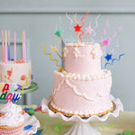 Pink tiered birthday cake topped with Meri Meri Pastel Swirly Candles and star toppers