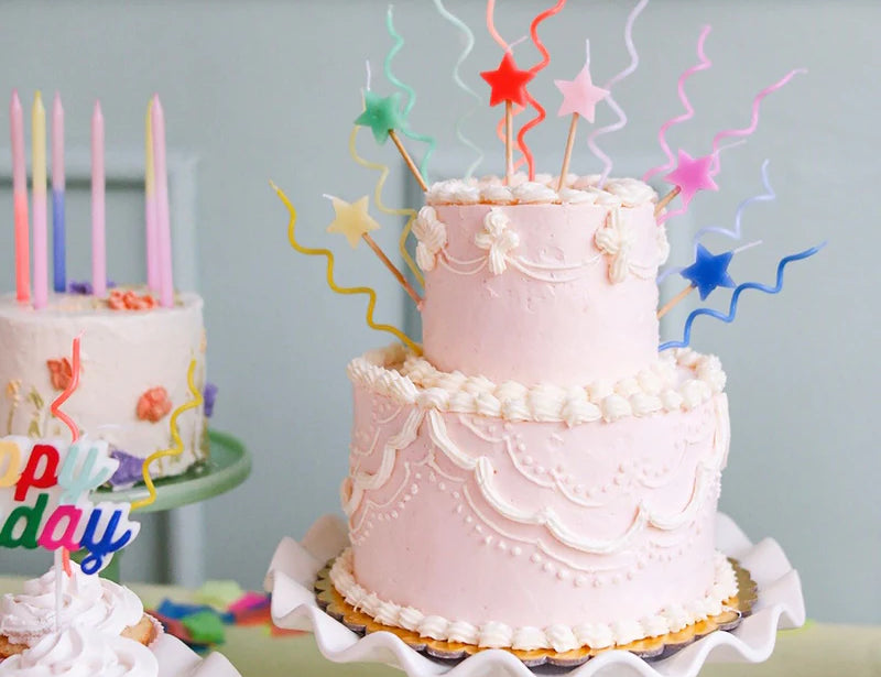 Pink tiered birthday cake topped with Meri Meri Pastel Swirly Candles and star toppers