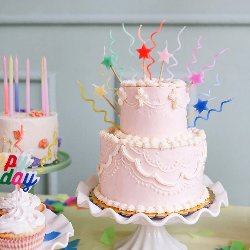 Pink tiered birthday cake topped with Meri Meri Pastel Swirly Candles and star toppers