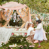Two girls in princess dresses at a garden party decorated with the Meri Meri Princess Party Garland