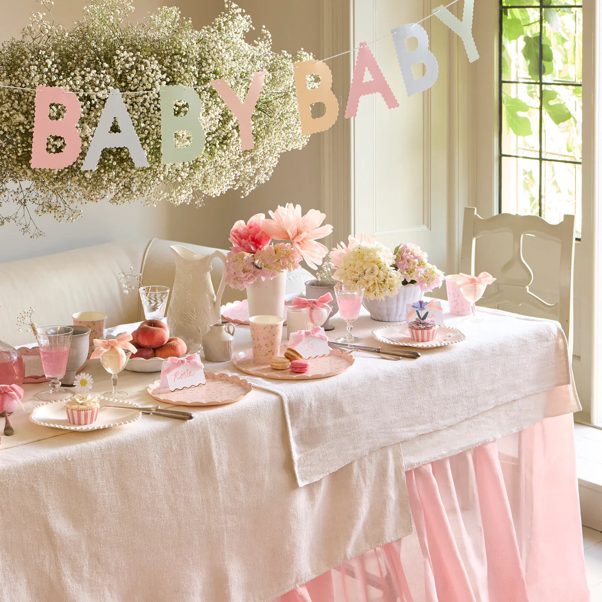 Meri Meri Scallop Edge Baby Garland hung over a baby shower table with flowers and cakes