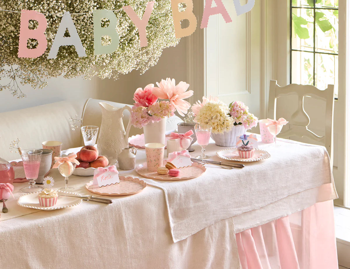 Meri Meri Scallop Edge Baby Garland hung over a baby shower table with flowers and cakes