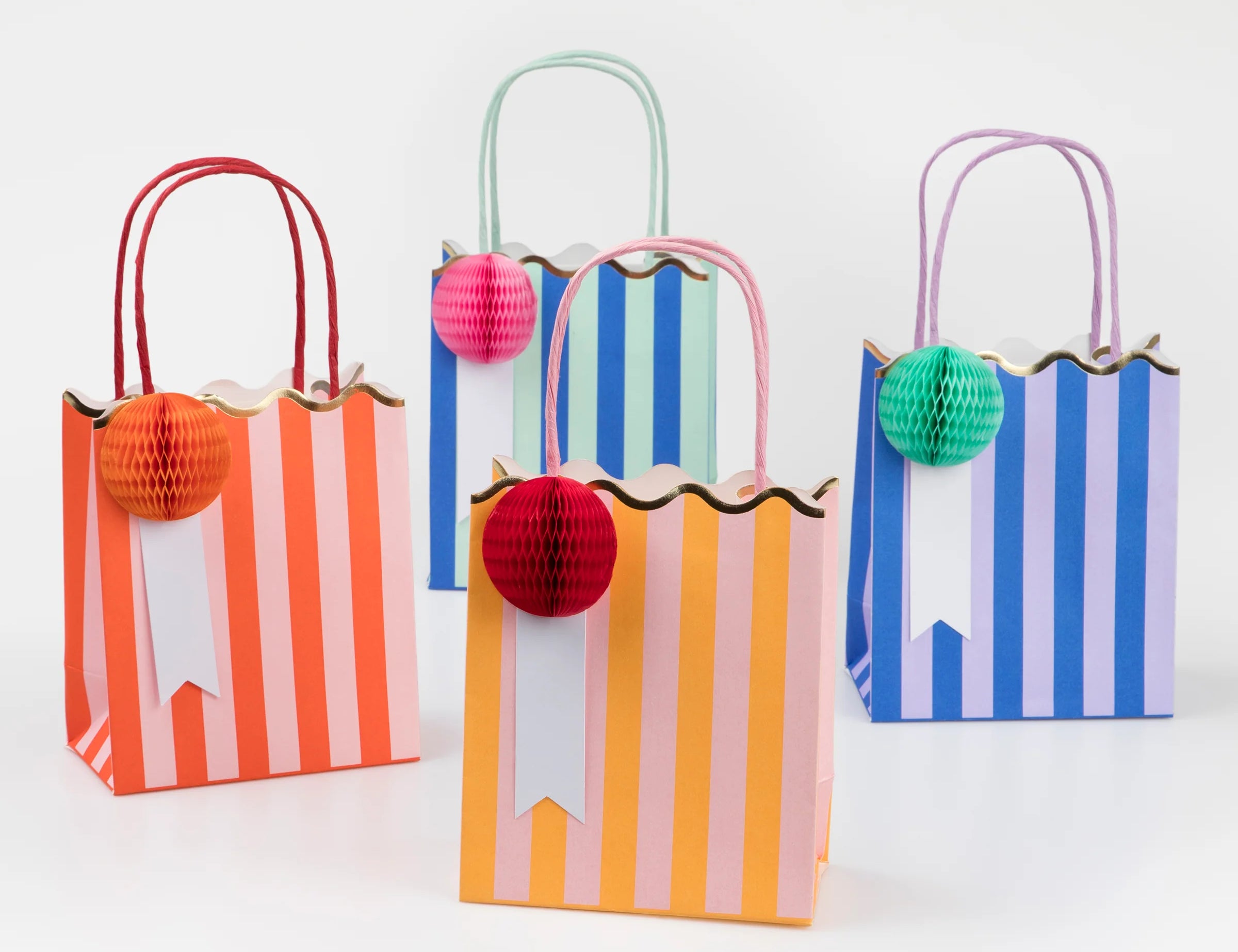 Meri Meri Stripe Party Bags in red, green, blue and orange stripes with honeycomb pom-poms and rope handles