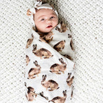 Milkbarn bamboo muslin swaddle wrapped around a newborn with a bunny print and white bow headband