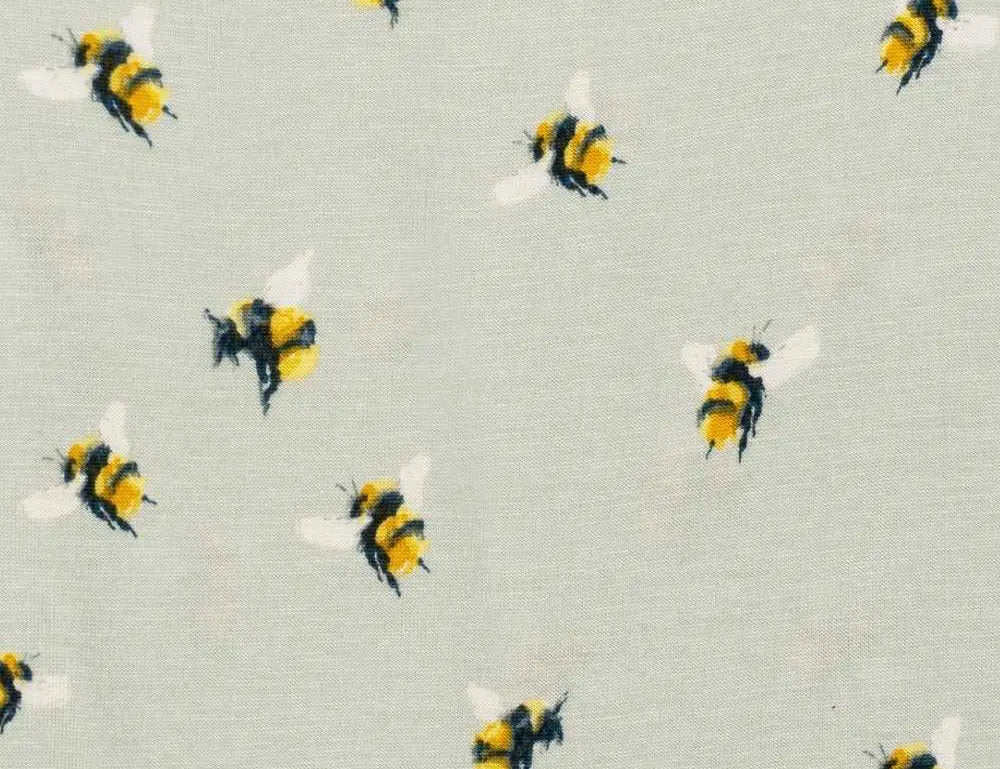 Close-up of the yellow and black bumblebee print on the sage Milkbarn Bumblebee Footed Romper