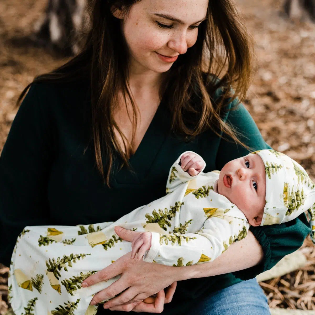 Mother holding a newborn dressed in the Milkbarn Camping Newborn Gown & Hat Set