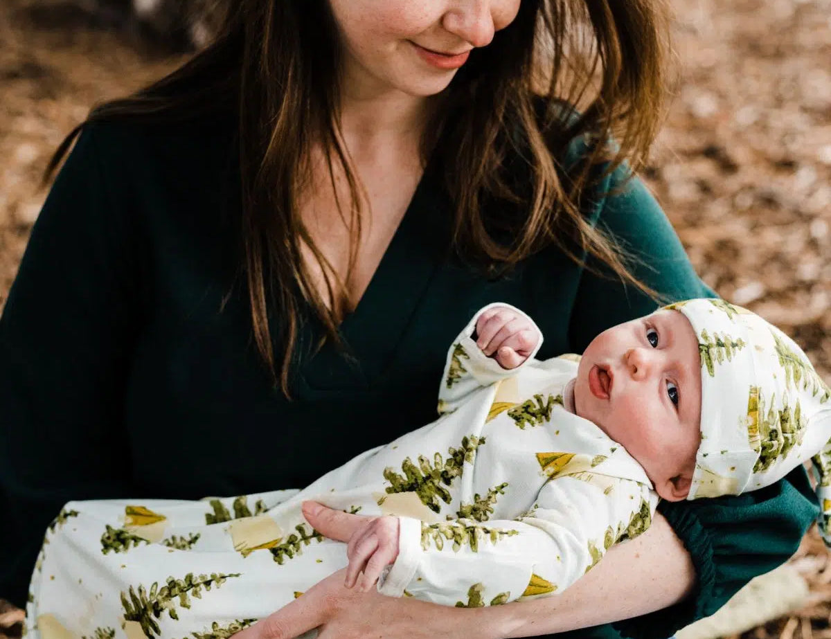 Mother holding a newborn dressed in the Milkbarn Camping Newborn Gown & Hat Set