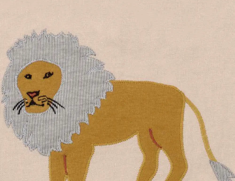 Close-up of the appliqued mustard lion with a gray mane on the Milkbarn Lion Linen Two-Layer Bib