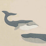 Close-up of the two embroidered gray whales on the Milkbarn Whale Linen Two-Layered Bib