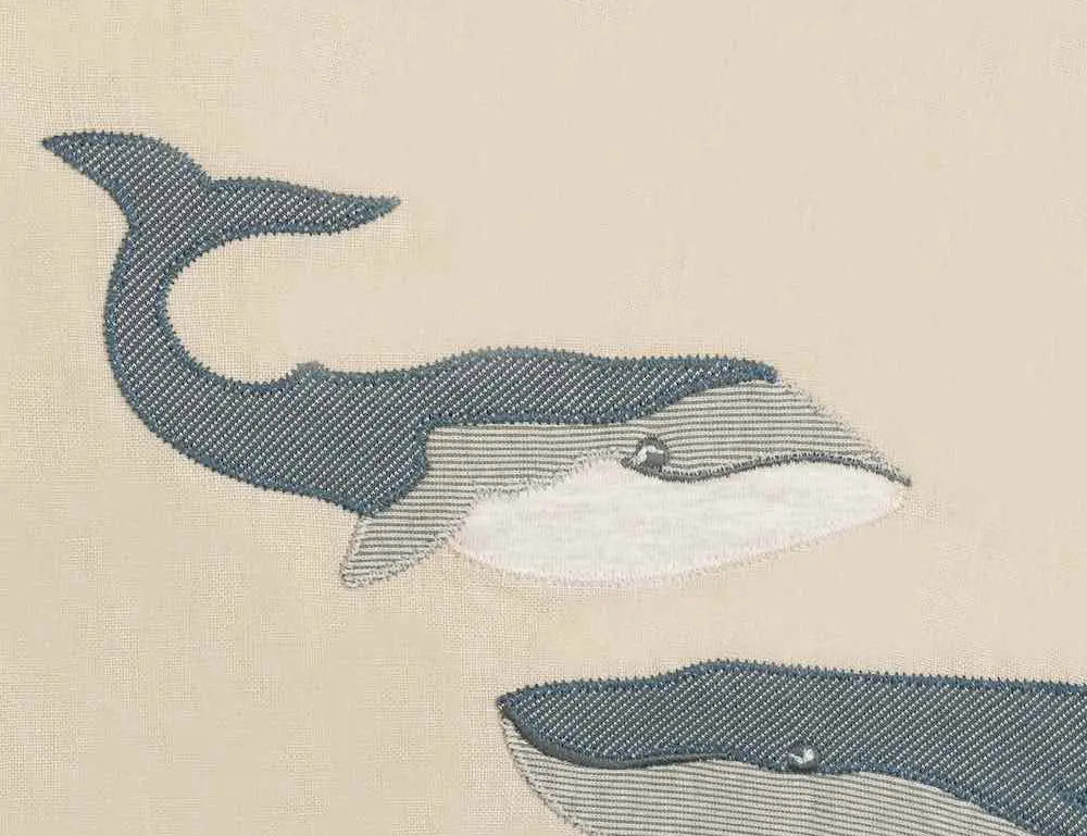 Close-up of the two embroidered gray whales on the Milkbarn Whale Linen Two-Layered Bib
