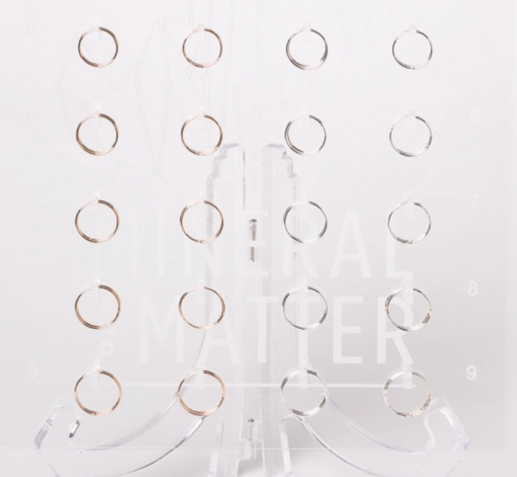 Mineral and Matter Stacking Rings, thin gold rings displayed on a clear acrylic stand