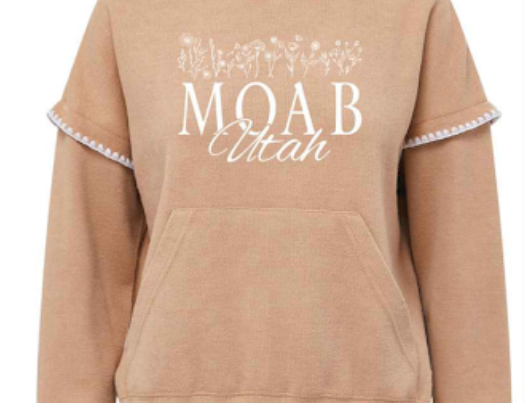 Praline Moab hoodie with white pom trim and a fine line wildflower print over Moab Utah