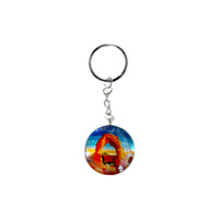 Round glass Moab keychain with Delicate Arch under a coral and peach sunset