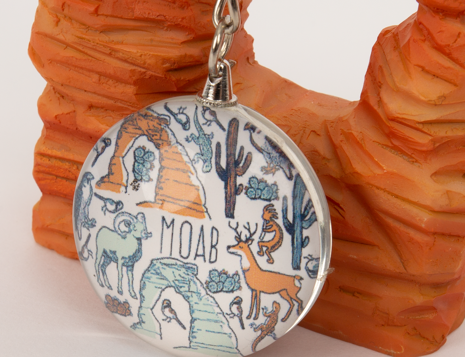 Round glass Moab keychain patterned with desert animals, cacti and arches in fine linework, second view