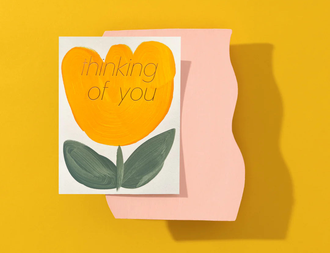 Moglea Flower Thinking of You Card styled on a mustard yellow surface with a pink paper shape