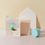 Moglea Moon Baby Card styled with pastel paper shapes and a white envelope