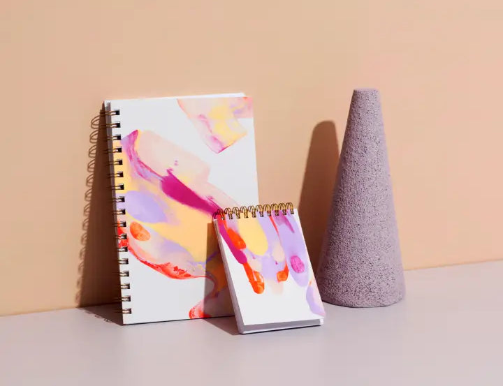 Moglea Painted Notebooks in Beam in two sizes leaning against a wall with a purple cone