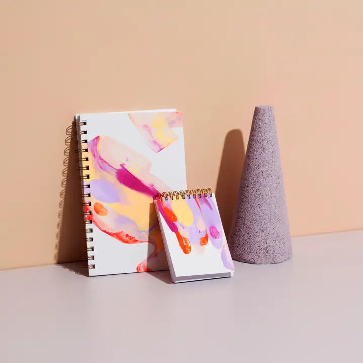 Moglea Painted Notebooks in Beam in two sizes leaning against a wall with a purple cone