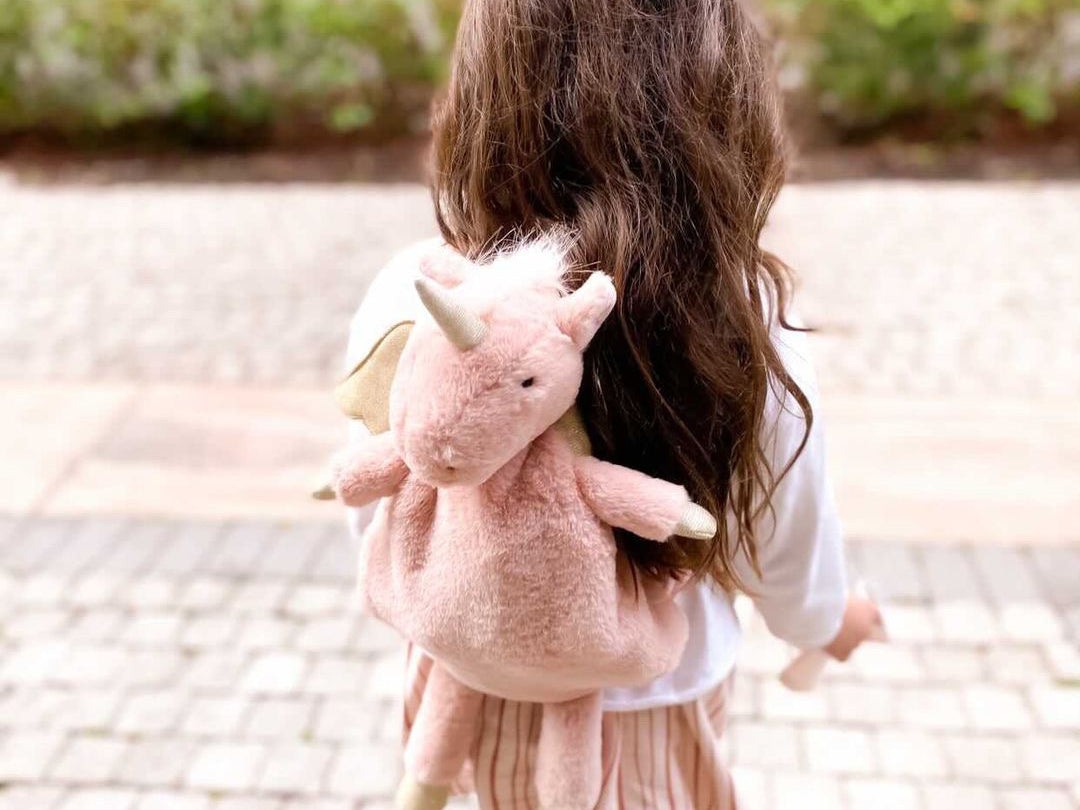 Girl with long dark hair wearing the Mon Ami Luna Unicorn Backpack, back view