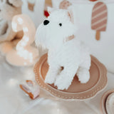 Mon Ami Wes The Westie plush sitting on a pink cake stand at a party