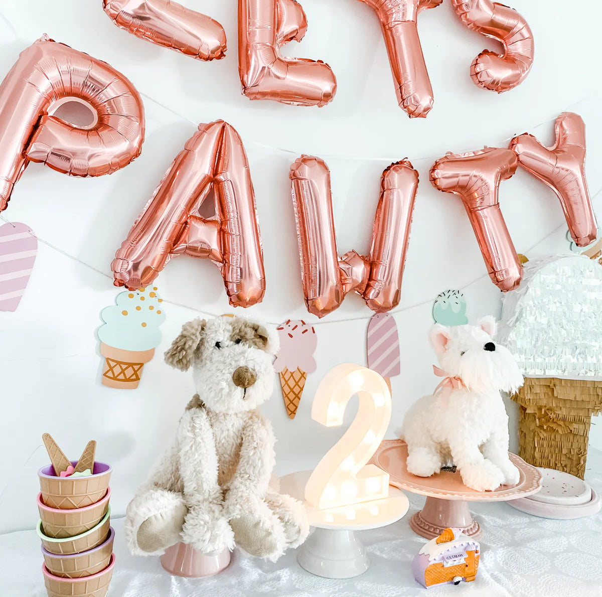 Mon Ami Wes The Westie plush at a puppy party with rose gold Let's Pawty balloons