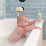 Mushie Bath Essentials Kit, a baby splashing in a white bathtub with blue tile
