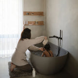 Mushie Bath Essentials Kit, a parent bathing a child in a grey freestanding tub
