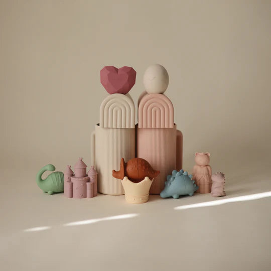 Mushie Bath Essentials Kit, pastel stacking bath toys and dinosaurs arranged in soft light