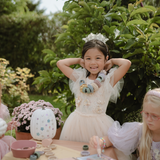 Girl in a tulle dress and flower crown at a garden table with the Mushie Fairies Reusable Water Color Pad