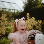 Laughing girl in a pink dress at a garden table with the Mushie Fairies Reusable Water Color Pad